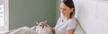 Middle age Caucasian woman sitting in bed with pet. Young woman stroking oriental cat. Friendship of human and domestic animal.