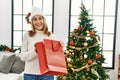 Middle age caucasian woman smiling confident opening christmas gift bag at home Royalty Free Stock Photo