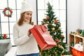 Middle age caucasian woman smiling confident opening christmas gift bag at home Royalty Free Stock Photo