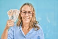 Middle age caucasian woman smiling happy holding uk pounds banknotes standing at the city