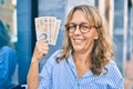 Middle age caucasian woman smiling happy holding uk pounds banknotes standing at the city