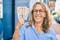 Middle age caucasian woman smiling happy holding uk pounds banknotes standing at the city