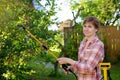 Middle age caucasian woman sprays trees against pests, vermin or diseases plants