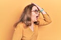 Middle age caucasian woman wearing casual clothes and glasses surprised with hand on head for mistake, remember error Royalty Free Stock Photo