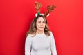 Middle age caucasian woman wearing cute christmas reindeer horns skeptic and nervous, frowning upset because of problem