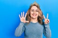 Middle age caucasian woman wearing queen crown showing and pointing up with fingers number seven while smiling confident and happy