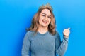 Middle age caucasian woman wearing queen crown smiling with happy face looking and pointing to the side with thumb up Royalty Free Stock Photo