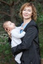 Middle age Caucasian woman with infant on arms, portrait outdoor