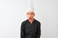 Middle age chef woman wearing uniform and hat standing over isolated white background afraid and shocked with surprise expression, Royalty Free Stock Photo