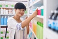 Middle age chinese woman customer holding toothpaste bottle on shelving at pharmacy Royalty Free Stock Photo