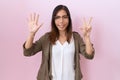 Middle age chinese woman wearing glasses over pink background showing and pointing up with fingers number eight while smiling Royalty Free Stock Photo