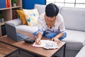 Middle age chinese woman writing on notebook accounting at home