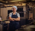 A middle age cook wearing a uniform standing with her arms crossed at restaurant`s kitchen. Royalty Free Stock Photo
