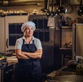 A middle age cook wearing a uniform standing with her arms crossed at restaurant`s kitchen. Royalty Free Stock Photo