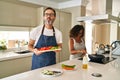 Middle age couple cooking mediterranean food at home looking at the camera blowing a kiss being lovely and sexy