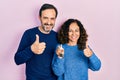 Middle age couple of hispanic woman and man holding keys of new home doing happy thumbs up gesture with hand Royalty Free Stock Photo