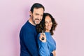 Middle age couple of hispanic woman and man holding keys of new home looking to side, relax profile pose with natural face and Royalty Free Stock Photo