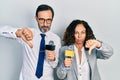 Middle age couple of hispanic woman and man holding reporter microphones with angry face, negative sign showing dislike with Royalty Free Stock Photo