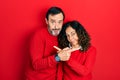 Middle age couple of hispanic woman and man hugging and standing together pointing to both sides with fingers, different direction Royalty Free Stock Photo