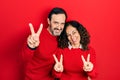 Middle age couple of hispanic woman and man hugging and standing together smiling with tongue out showing fingers of both hands Royalty Free Stock Photo