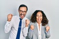 Middle age couple of hispanic woman and man wearing business office uniform celebrating surprised and amazed for success with arms Royalty Free Stock Photo