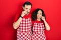 Middle age couple of hispanic woman and man wearing cook apron mouth and lips shut as zip with fingers Royalty Free Stock Photo