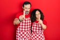 Middle age couple of hispanic woman and man wearing cook apron pointing with finger up and angry expression, showing no gesture Royalty Free Stock Photo