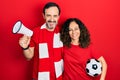 Middle age couple of hispanic woman and man wearing team scarf cheering game holding megaphone and ball smiling with a happy and Royalty Free Stock Photo