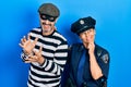 Middle age couple of hispanic woman and man wearing thief and police uniform with hand on chin thinking about question, pensive