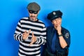 Middle age couple of hispanic woman and man wearing thief and police uniform with hand on chin thinking about question, pensive