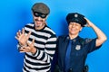 Middle age couple of hispanic woman and man wearing thief and police uniform smiling confident touching hair with hand up gesture,