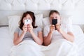 Middle age couple hold cell phones in bedroom, modern family