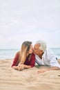 Middle age couple in love lying on the sand at the beach kissing happy and cheerful together Royalty Free Stock Photo