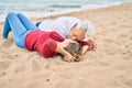 Middle age couple in love lying on the sand at the beach kissing happy and cheerful together Royalty Free Stock Photo