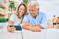 Middle age couple in love sitting at the terrace of coffee shop using smartphone happy and cheerful together Royalty Free Stock Photo