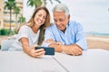 Middle age couple in love sitting at the terrace of coffee shop using smartphone happy and cheerful together Royalty Free Stock Photo