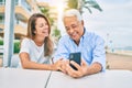 Middle age couple in love sitting at the terrace of coffee shop using smartphone happy and cheerful together Royalty Free Stock Photo