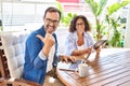 Middle age couple relaxing at home terrace pointing thumb up to the side smiling happy with open mouth Royalty Free Stock Photo