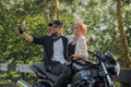 Middle age couple riding a motorcycle having fun and taking a selfie on a mobile phone camera Royalty Free Stock Photo
