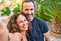 Middle age couple wearing casual clothes smiling happy making selfie by the camera at the forest