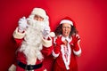 Middle age couple wearing Santa costume and glasses over isolated red background smiling funny doing claw gesture as cat, Royalty Free Stock Photo