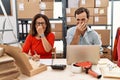 Middle age couple working at small business ecommerce smelling something stinky and disgusting, intolerable smell, holding breath Royalty Free Stock Photo