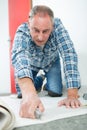 Middle-age craftsman cutting carpet with cutter Royalty Free Stock Photo