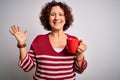 Middle age curly hair woman drinking mug of coffee over isolated white background very happy and excited, winner expression Royalty Free Stock Photo