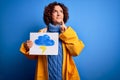 Middle age curly hair woman wearing rain coat holding banner with cloud and thunder serious face thinking about question, very