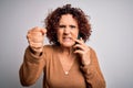 Middle age curly woman having conversation talking on the smartphone over white background annoyed and frustrated shouting with Royalty Free Stock Photo