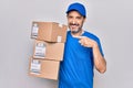 Middle age delivery man wearing cap holding package over isolated white background smiling happy pointing with hand and finger Royalty Free Stock Photo
