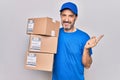 Middle age delivery man wearing cap holding package over isolated white background smiling happy pointing with hand and finger to Royalty Free Stock Photo