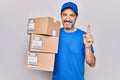 Middle age delivery man wearing cap holding package over isolated white background smiling with an idea or question pointing Royalty Free Stock Photo