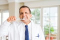 Middle age dentist man holding toothbrush and smiling Royalty Free Stock Photo